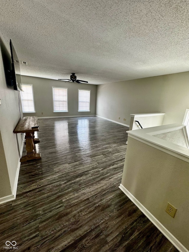 12583 Courage Xing, Fishers, IN 46037 - unfurnished living room featuring dark wood-type flooring, a ceiling fan, healthy amount of natural light, and a textured ceiling
