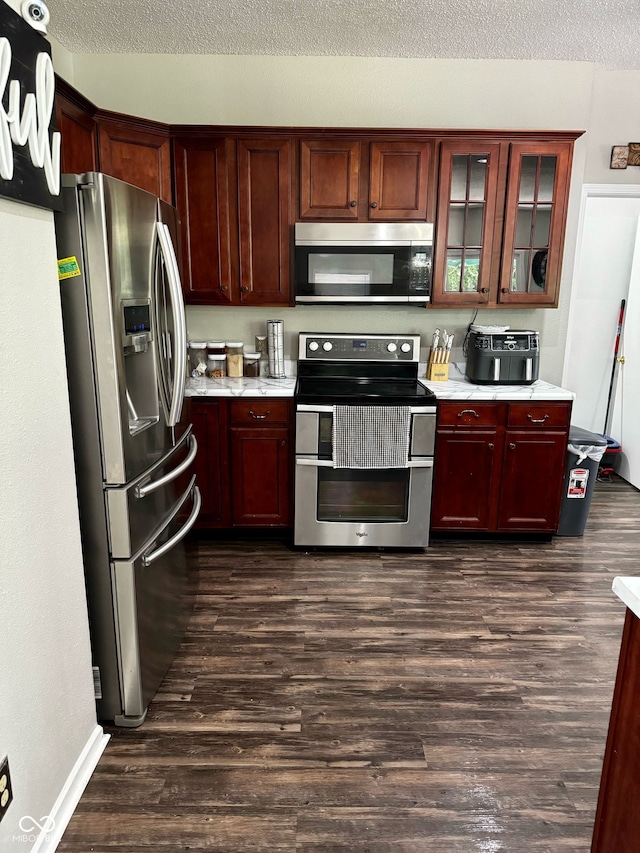 12583 Courage Xing, Fishers, IN 46037 - kitchen with appliances with stainless steel finishes, light countertops, dark wood finished floors, glass insert cabinets, and a textured ceiling
