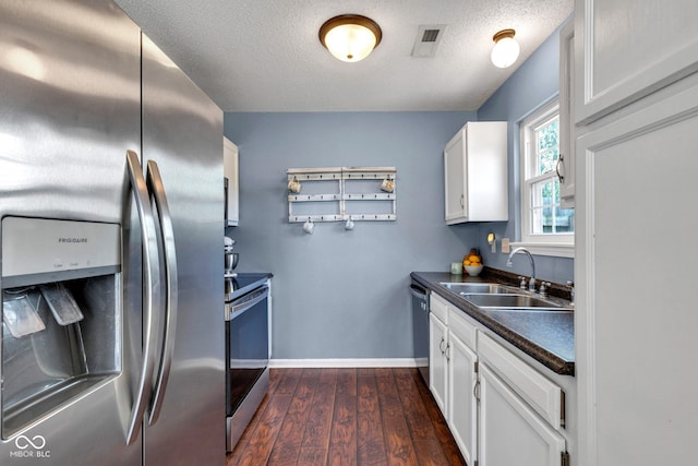 7702 Wood Stream Dr, Indianapolis, IN 46239 - kitchen with stainless steel appliances, dark countertops, dark wood-type flooring, white cabinets, and a textured ceiling