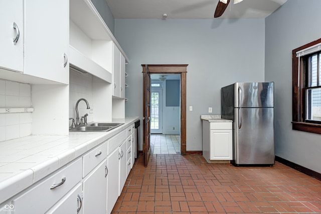 832 Noble St, Indianapolis, IN 46203 - kitchen with appliances with stainless steel finishes, tile counters, white cabinets, a ceiling fan, and brick floors