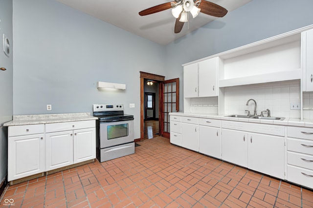 832 Noble St, Indianapolis, IN 46203 - kitchen with electric stove, a ceiling fan, backsplash, white cabinetry, and brick patterned floors