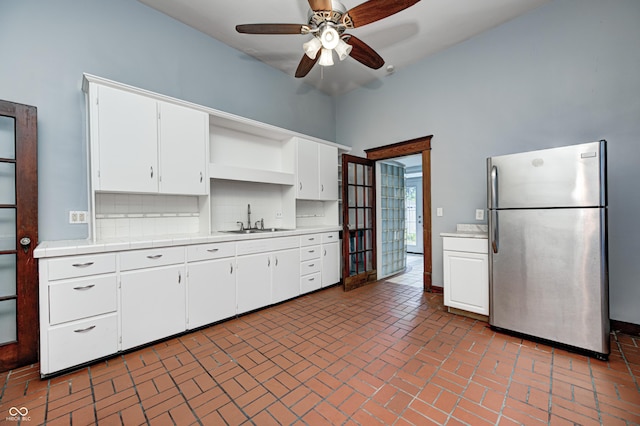 832 Noble St, Indianapolis, IN 46203 - kitchen with freestanding refrigerator, open shelves, ceiling fan, brick floors, and white cabinets