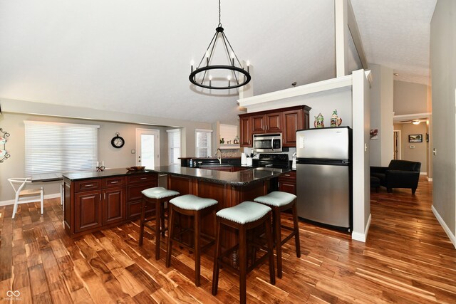 114 Sunrise Ln, Lizton, IN 46149 - kitchen featuring appliances with stainless steel finishes, dark countertops, a breakfast bar, wood finished floors, and a chandelier