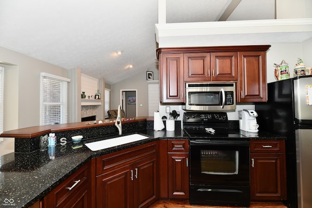 114 Sunrise Ln, Lizton, IN 46149 - kitchen with stainless steel appliances, a peninsula, vaulted ceiling, dark stone counters, and a fireplace