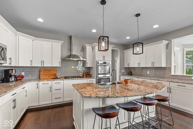 16338 Portage Trail Ln, Fortville, IN 46040 - kitchen with wall chimney range hood, appliances with stainless steel finishes, white cabinets, tasteful backsplash, and recessed lighting