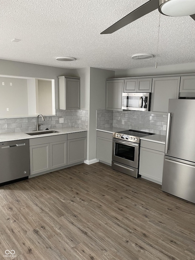 9701 W Constellation Dr, Pendleton, IN 46064 - kitchen featuring stainless steel appliances, gray cabinetry, backsplash, light countertops, and a textured ceiling