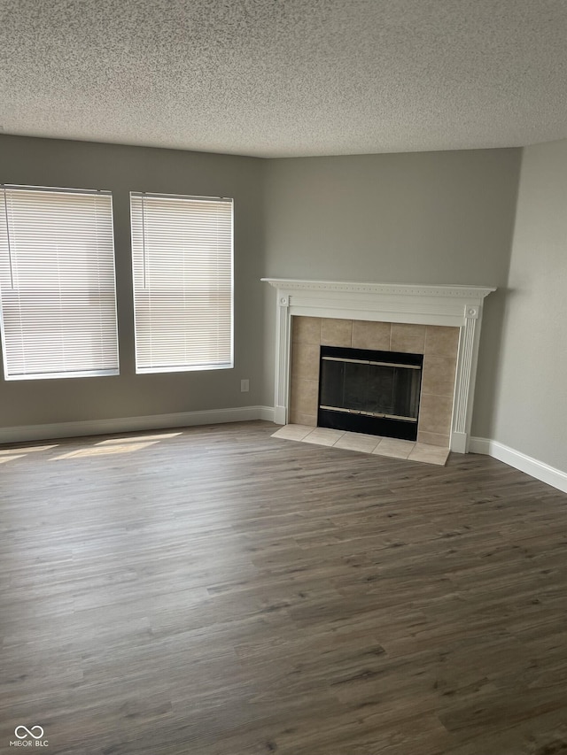 9701 W Constellation Dr, Pendleton, IN 46064 - unfurnished living room featuring a tile fireplace, a textured ceiling, and wood finished floors