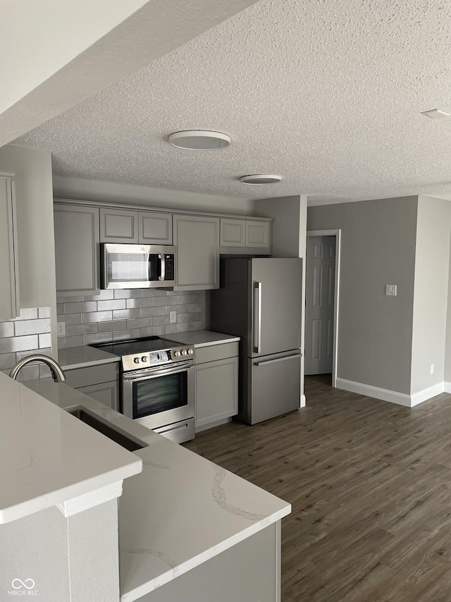 9701 W Constellation Dr, Pendleton, IN 46064 - kitchen featuring stainless steel appliances, gray cabinetry, a textured ceiling, dark wood finished floors, and decorative backsplash