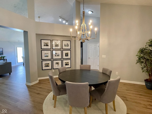 8202 Stonelick Dr, Avon, IN 46123 - dining room with wood finished floors, a chandelier, track lighting, a towering ceiling, and a textured ceiling