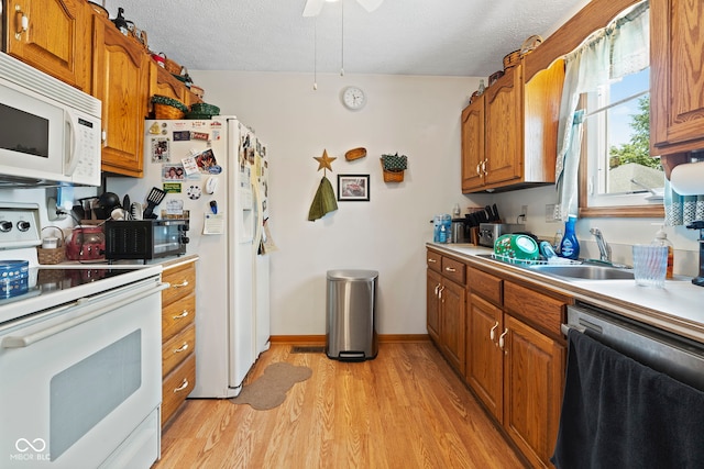 1044 Miller St, Clinton, IN 47842 - kitchen featuring white appliances, a textured ceiling, brown cabinets, light wood finished floors, and light countertops