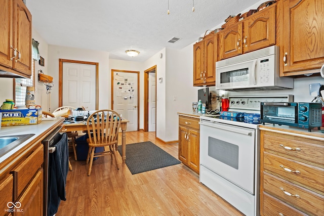 1044 Miller St, Clinton, IN 47842 - kitchen featuring white appliances, light wood-type flooring, brown cabinetry, and light countertops