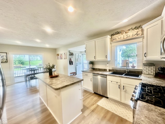 513 N Main St, Veedersburg, IN 47987 - kitchen with appliances with stainless steel finishes, a textured ceiling, a center island, light wood finished floors, and plenty of natural light