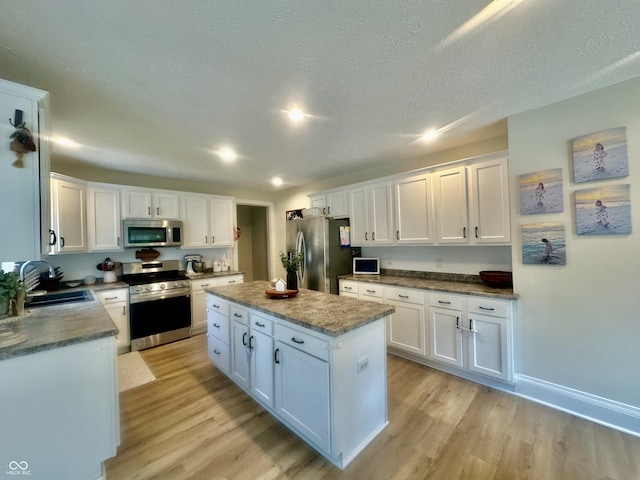 513 N Main St, Veedersburg, IN 47987 - kitchen featuring stainless steel appliances, light wood-style flooring, white cabinetry, and a textured ceiling