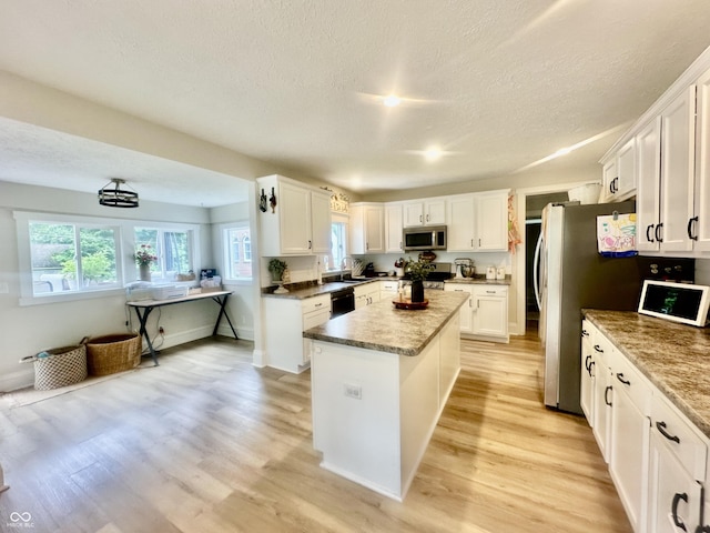 513 N Main St, Veedersburg, IN 47987 - kitchen with stainless steel microwave, dishwasher, a center island, light wood finished floors, and white cabinets