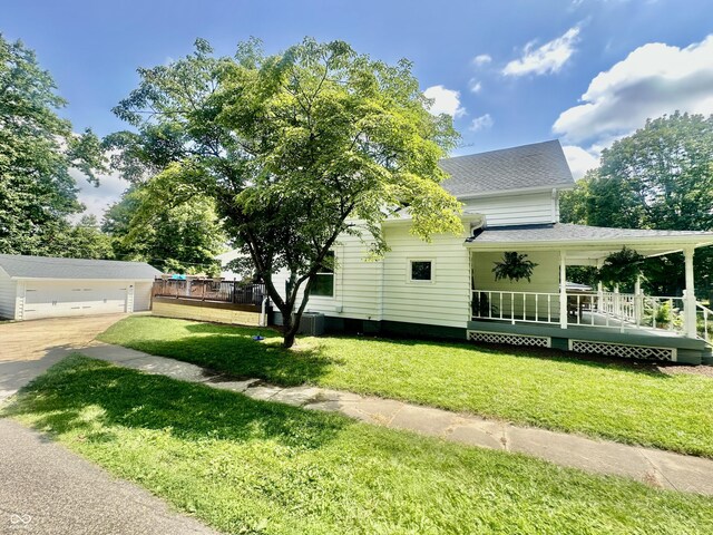 513 N Main St, Veedersburg, IN 47987 - view of front facade with roof with shingles, covered porch, an outdoor structure, and a front lawn