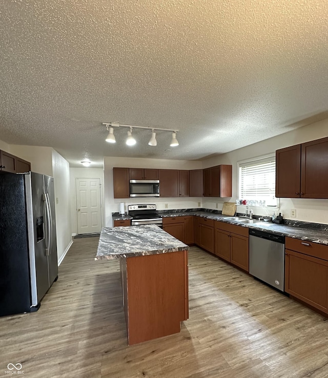 2964 Sentiment Ln, Greenwood, IN 46143 - kitchen with appliances with stainless steel finishes, a textured ceiling, dark countertops, light wood-style flooring, and a center island