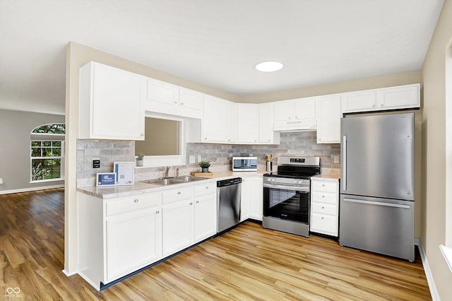 3084 Armory Dr, Indianapolis, IN 46208 - kitchen with stainless steel appliances, under cabinet range hood, light countertops, and white cabinetry