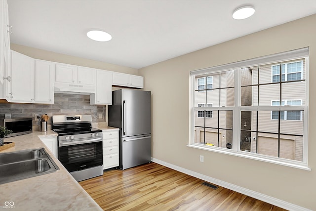 3084 Armory Dr, Indianapolis, IN 46208 - kitchen with stainless steel appliances, under cabinet range hood, light countertops, backsplash, and light wood finished floors