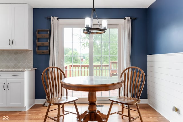 7045 W 100 N, Greenfield, IN 46140 - dining space with a chandelier, light wood-style flooring, healthy amount of natural light, and wooden walls
