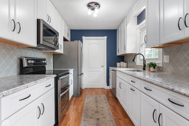 7045 W 100 N, Greenfield, IN 46140 - kitchen featuring stainless steel appliances, light wood-type flooring, tasteful backsplash, and white cabinetry