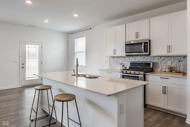 6143 Madera Dr, Whitestown, IN 46075 - kitchen featuring appliances with stainless steel finishes, dark wood-type flooring, an island with sink, tasteful backsplash, and white cabinetry