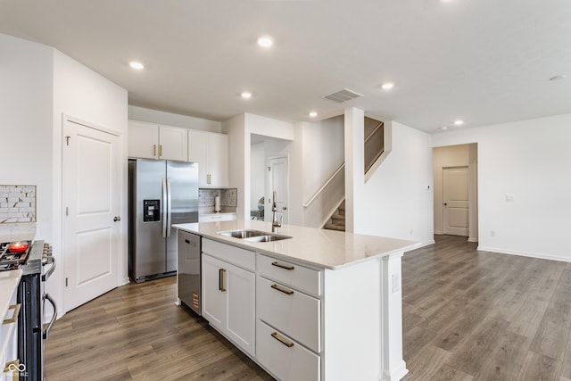 6143 Madera Dr, Whitestown, IN 46075 - kitchen featuring appliances with stainless steel finishes, tasteful backsplash, light wood-style floors, white cabinetry, and a center island with sink