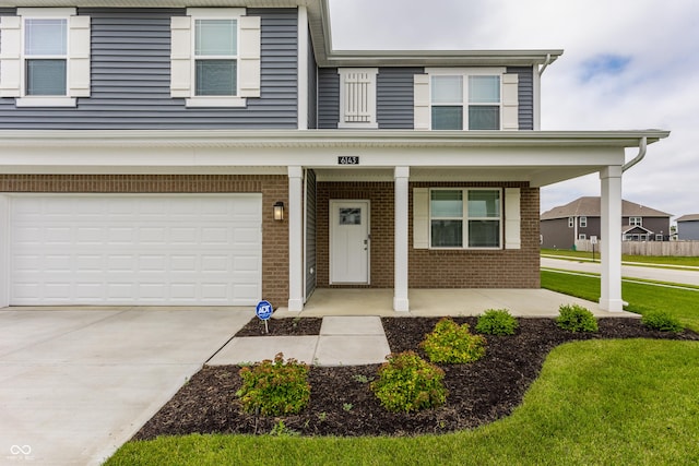 6143 Madera Dr, Whitestown, IN 46075 - view of front of property featuring brick siding, covered porch, a garage, concrete driveway, and a front lawn