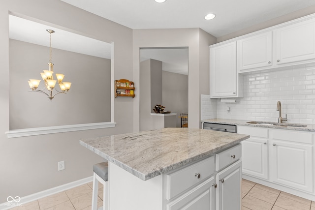 866 Rosalind Pl, Carmel, IN 46032 - kitchen with backsplash, light stone countertops, white cabinetry, a chandelier, and a center island