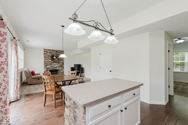12291 Cobblestone Dr, Fishers, IN 46037 - kitchen featuring wood finished floors, a stone fireplace, a center island, open floor plan, and pendant lighting