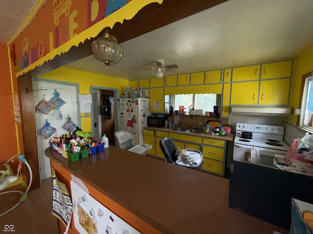 3209 Forest Ter, Anderson, IN 46013 - kitchen with under cabinet range hood, white appliances, yellow cabinetry, and ceiling fan