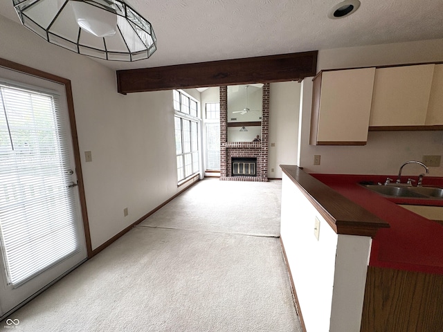 6458 Watham Ct, Indianapolis, IN 46250 - kitchen featuring light carpet, dark countertops, a brick fireplace, beamed ceiling, and white cabinets