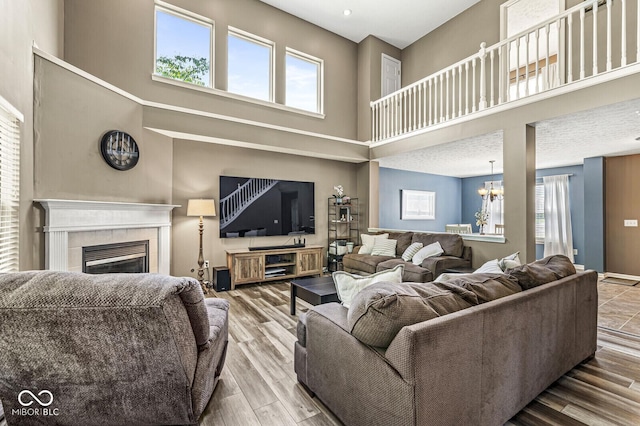 12034 Gatwick View Dr, Fishers, IN 46037 - living area featuring a high ceiling, plenty of natural light, a fireplace, a chandelier, and wood finished floors