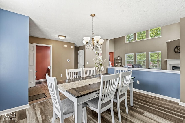 12034 Gatwick View Dr, Fishers, IN 46037 - dining room with a textured ceiling, a chandelier, wood finished floors, and a fireplace