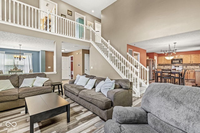 12034 Gatwick View Dr, Fishers, IN 46037 - living room with a chandelier, wood finished floors, a high ceiling, and stairs