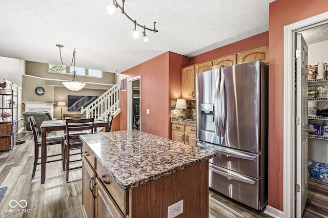 12034 Gatwick View Dr, Fishers, IN 46037 - kitchen featuring stainless steel fridge, a textured ceiling, light wood-style floors, a kitchen island, and hanging light fixtures
