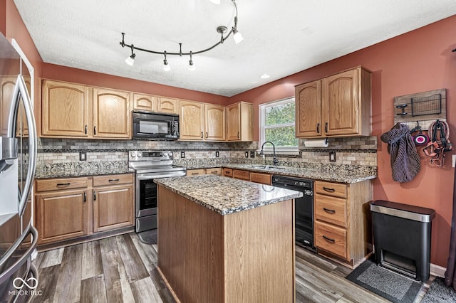 12034 Gatwick View Dr, Fishers, IN 46037 - kitchen with black appliances, wood finished floors, light stone countertops, a center island, and decorative backsplash