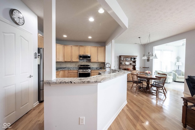 12985 Merlot Ln, Fishers, IN 46037 - kitchen featuring appliances with stainless steel finishes, light brown cabinets, light wood-type flooring, light stone counters, and decorative backsplash