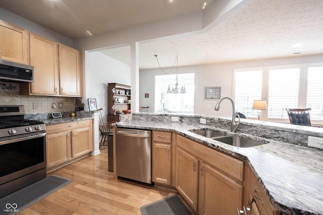 12985 Merlot Ln, Fishers, IN 46037 - kitchen with stainless steel appliances, light wood-style flooring, light stone counters, tasteful backsplash, and a chandelier