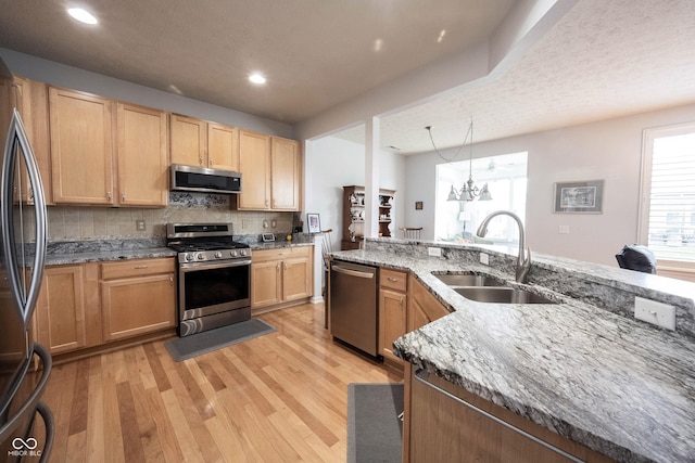 12985 Merlot Ln, Fishers, IN 46037 - kitchen featuring stainless steel appliances, light wood-style flooring, light stone countertops, tasteful backsplash, and light brown cabinetry