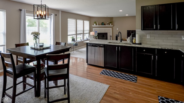 14521 Stewart Cir, Fishers, IN 46038 - kitchen with stainless steel dishwasher, a tiled fireplace, a peninsula, light wood-style flooring, and recessed lighting