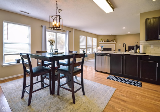 14521 Stewart Cir, Fishers, IN 46038 - dining space with light wood-style floors, a chandelier, a fireplace, recessed lighting, and a textured ceiling