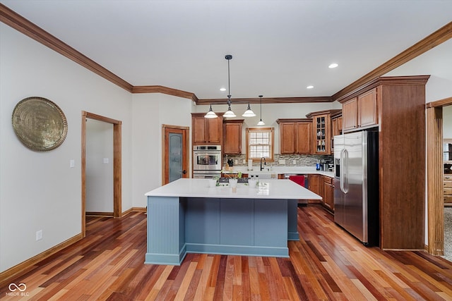 7178 Lockford Walk N, Avon, IN 46123 - kitchen featuring stainless steel appliances, brown cabinets, crown molding, a center island, and light countertops