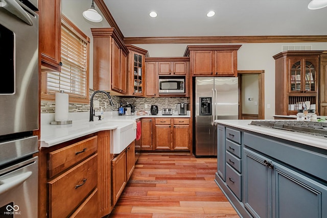 7178 Lockford Walk N, Avon, IN 46123 - kitchen with appliances with stainless steel finishes, ornamental molding, brown cabinets, light wood-style floors, and light countertops