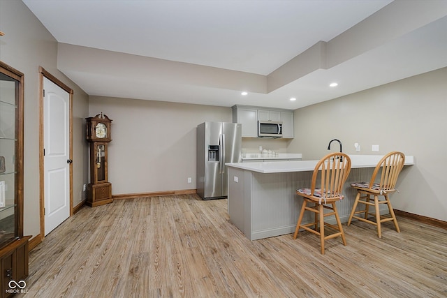 7178 Lockford Walk N, Avon, IN 46123 - kitchen with stainless steel appliances, light wood-style flooring, a peninsula, recessed lighting, and a breakfast bar
