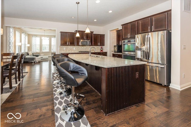 15540 Provincial Ln, Fishers, IN 46040 - kitchen featuring stainless steel appliances, dark brown cabinetry, recessed lighting, dark wood-style flooring, and light stone counters