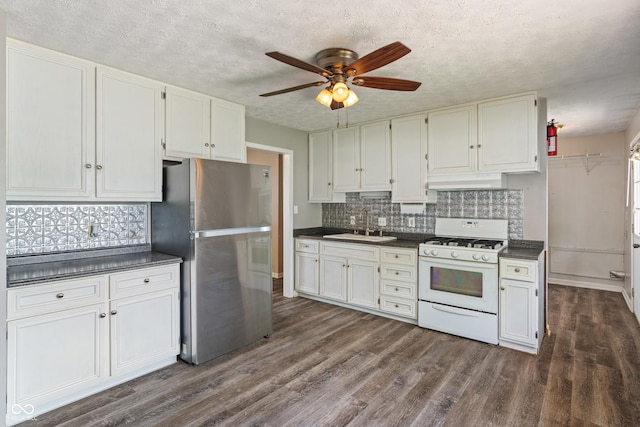 1108 Warwick Dr, New Whiteland, IN 46184 - kitchen with white gas range oven, freestanding refrigerator, dark countertops, a ceiling fan, and under cabinet range hood