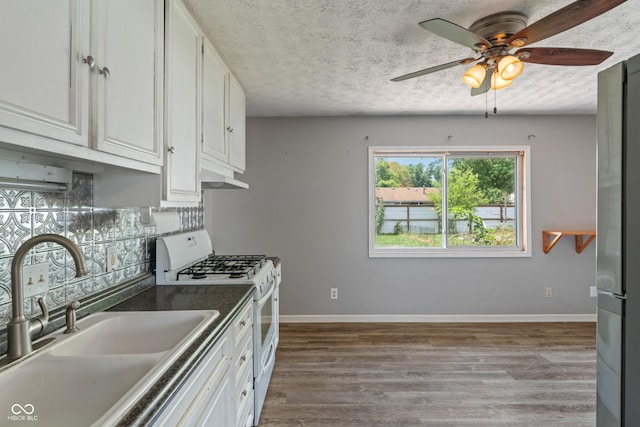 1108 Warwick Dr, New Whiteland, IN 46184 - kitchen with gas range gas stove, under cabinet range hood, dark wood-style floors, ceiling fan, and tasteful backsplash