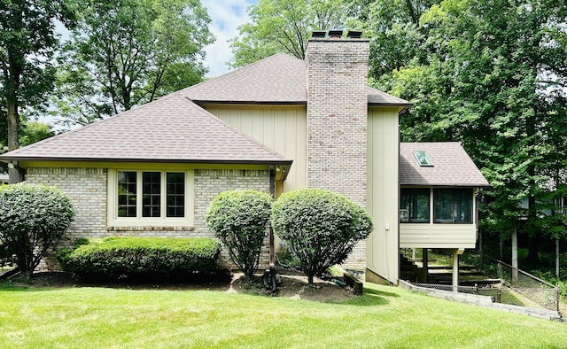 8413 Catamaran Dr, Indianapolis, IN 46236 - view of side of home with a shingled roof, a chimney, a lawn, and a sunroom