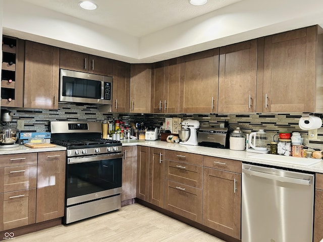 8413 Catamaran Dr, Indianapolis, IN 46236 - kitchen with stainless steel appliances, decorative backsplash, light countertops, light wood finished floors, and recessed lighting