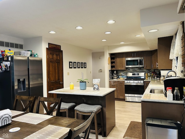 8413 Catamaran Dr, Indianapolis, IN 46236 - kitchen with appliances with stainless steel finishes, light wood-type flooring, recessed lighting, tasteful backsplash, and dark brown cabinetry